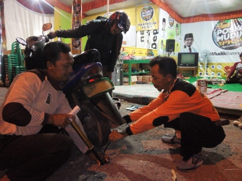 Kepanduan PKS Kota Bekasi sedang memperbaiki motor salah seorang pemudik