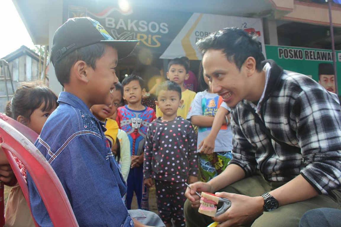 Seorang anak sedang mengikuti periksa gigi gratis dengan relawan Yaris