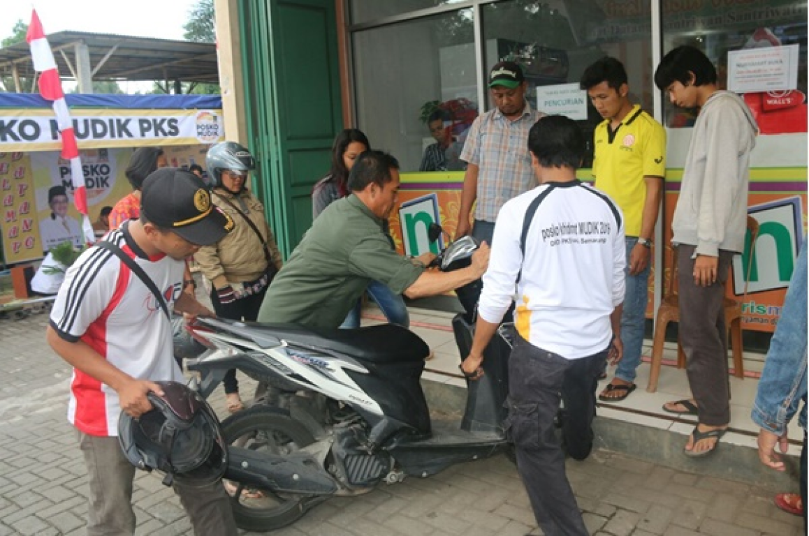 Beberapa kader PKS menolong pengendara motor yang jatuh tepat di depan Posko Mudik PKS Semarang.