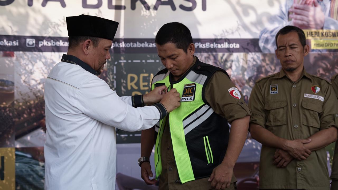 Ketua DPD PKS Kota Bekasi Heri Korswara memaikan seragam kepada petugas Posko Mudik PKS 2019 di Posko Mudik PKS Bekasi Jalan KH.Noer Ali Kalimalang Bekasi (dok PKSFoto)